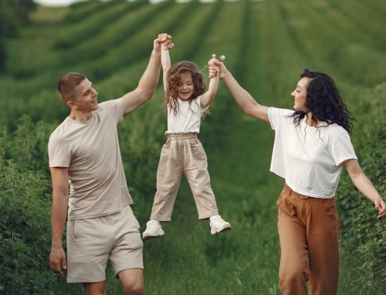Joyful family moment in a green field during summer, capturing love and playfulness.