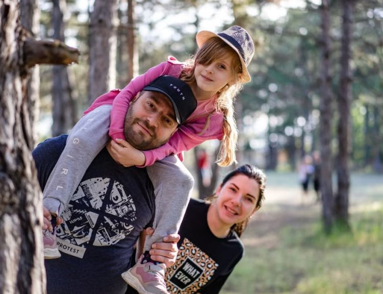A joyful family enjoying a playful day in a sunlit forest park, capturing the essence of togetherness.